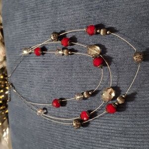 Three strand costume necklace with red, clear and black beads on a wired chain.